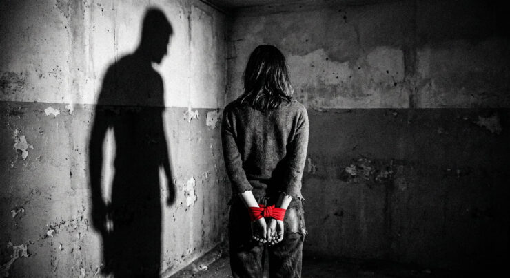 Mujer atada con cinta roja y sombra masculina amenazante: Metáfora de la violencia de género y el patriarcado.