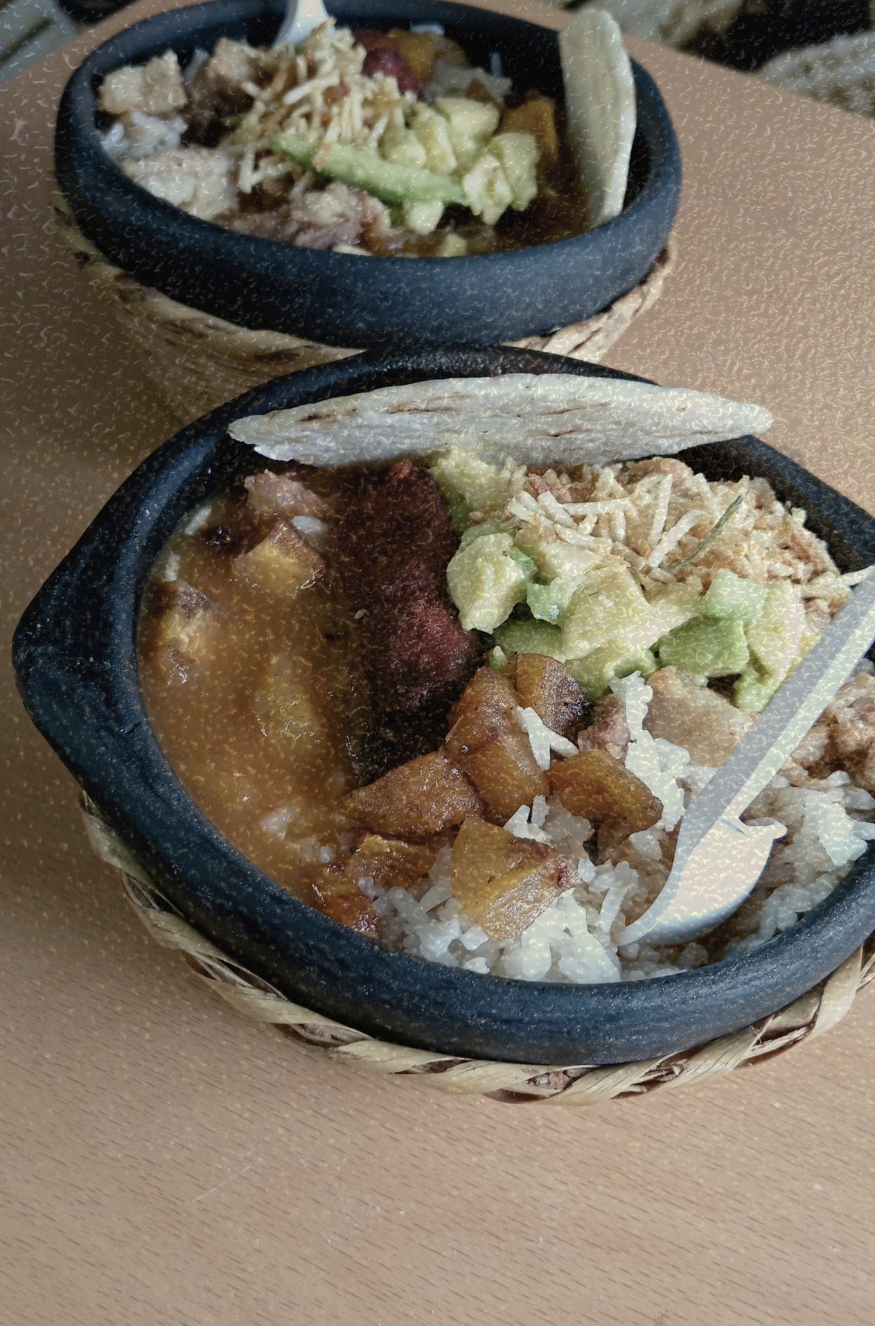 Fotografía cenital de dos cazuelas con frijoles, arroz, chicharrón crujiente, chorizo, aguacate y arepa blanca. Un bodegón cinematográfico que captura la esencia de la gastronomía popular y el ritual de la mesa como sistema de símbolos en KOKOGOA.