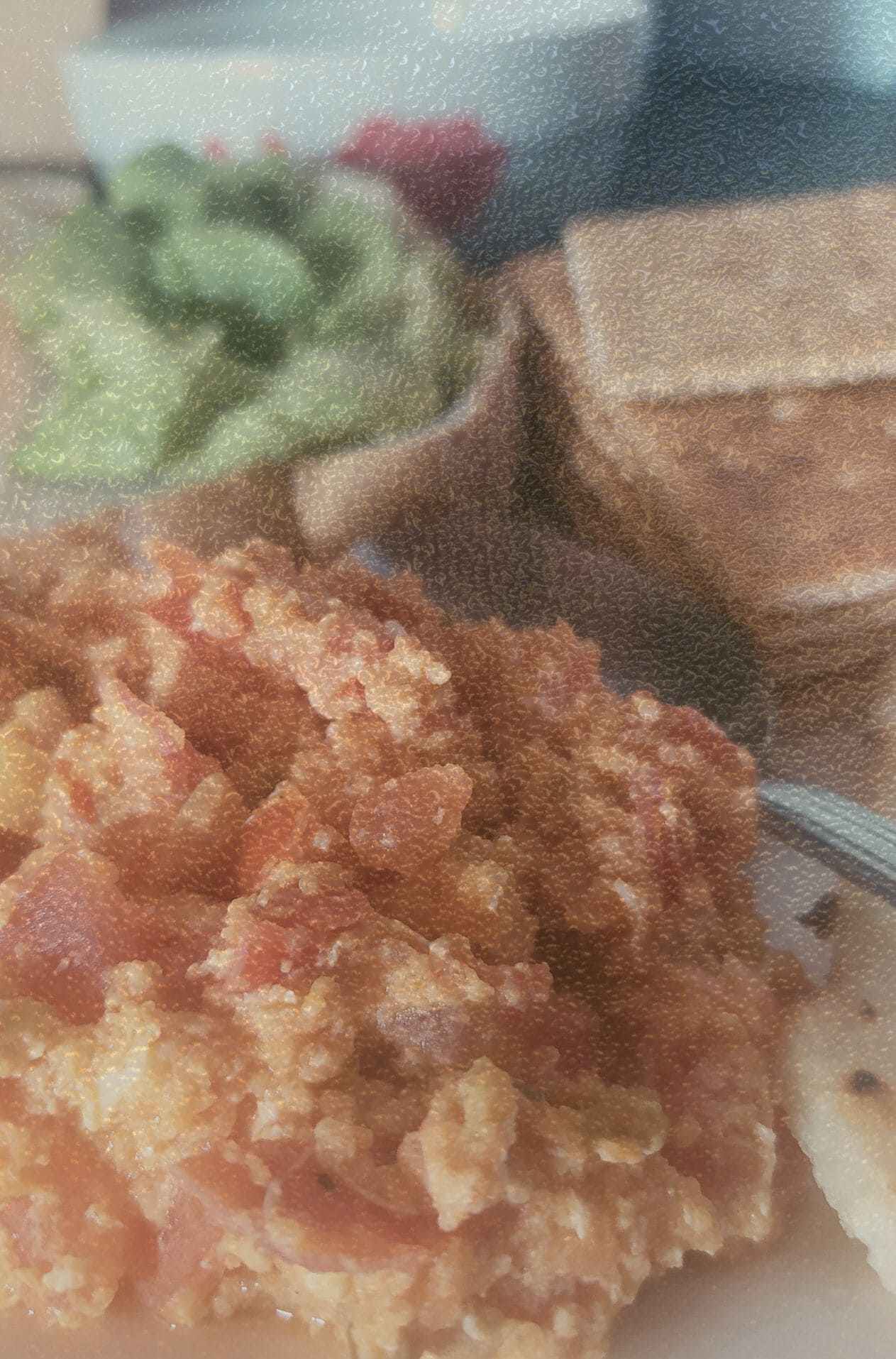 Fotografía de huevos revueltos con tomate, acompañados de galletas integrales y una porción de aguacate. Imagen con grano cinematográfico que forma parte del archivo de alimentación real KOKOGOA.