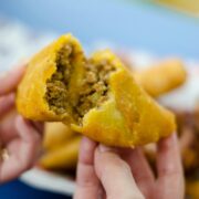 Crónica de la empanada colombiana: Primer plano de una empanada de maíz dorado abierta por la mitad, revelando un relleno jugoso de carne picada y vapor ascendente. La fotografía de Frederick Medina captura la textura crujiente y la esencia de la cocina callejera tradicional.
